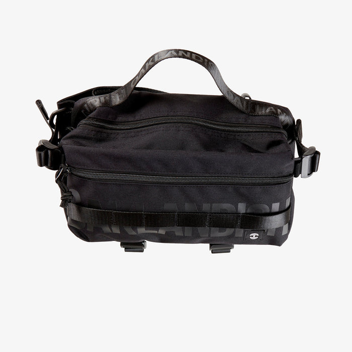 A black nylon hip bag with a black Oaklandish wordmark top zipper, front zipper, top handle, waist belt, & small white Oaklandish tree logo.