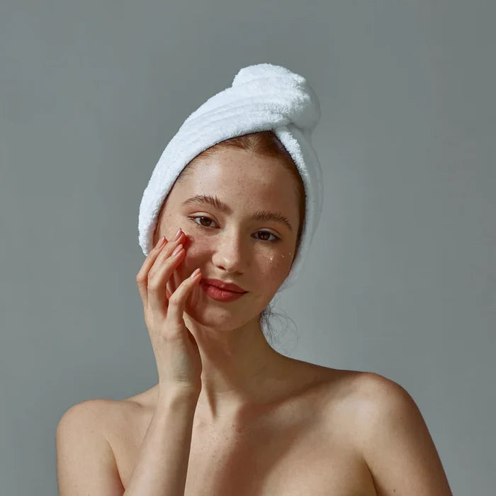 white woman white hair towel applying facial serums dermal essentials skincare