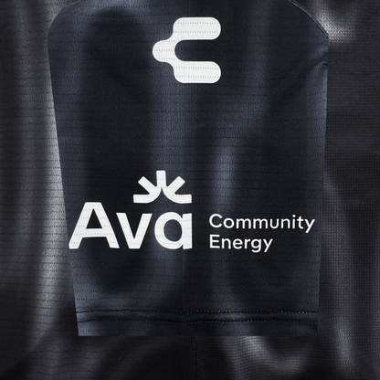 Close-up of black polyester fabric with a subtle dotted pattern, featuring bold white Oakland Soul logos and text, including the stylized "O" above "Ava Community Energy," all standing out clearly on the 2026 OAKLAND SOUL SC SPIRIT JERSEY.
