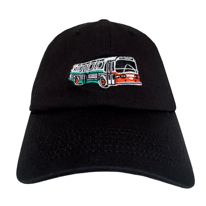 The Oaklandish AC Transit Dad Hat features a black design with an embroidered vintage AC Transit bus in green, white, and orange on the front—an homage to transit history viewed against a plain white background.