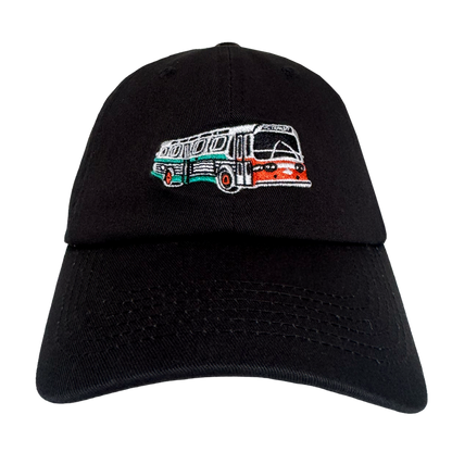 The Oaklandish AC Transit Dad Hat features a black design with an embroidered vintage AC Transit bus in green, white, and orange on the front—an homage to transit history viewed against a plain white background.