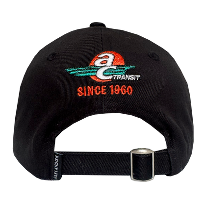 Back view of the AC Transit Dad Hat by Oaklandish, a black cap with an embroidered AC Transit logo (red sun, teal swooshes, "Since 1960" in orange), adjustable black strap with silver buckle, and Oaklandish label—celebrating East Bay pride.