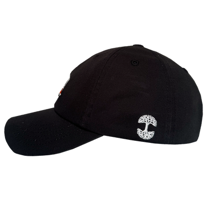 The Oaklandish AC Transit Dad Hat is a black, vintage-inspired cap with a curved brim, structured crown, ventilation eyelets, and a white embroidered logo resembling a stylized tree near the back. Shown from the side against a plain white background.