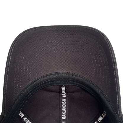 Top-down view of the inside of the AC Transit Dad Hat by Oaklandish. The inner seams feature repeating white "OAKLANDISH" text, celebrating East Bay pride. Its curved brim and stitching details stand out against a plain white background.