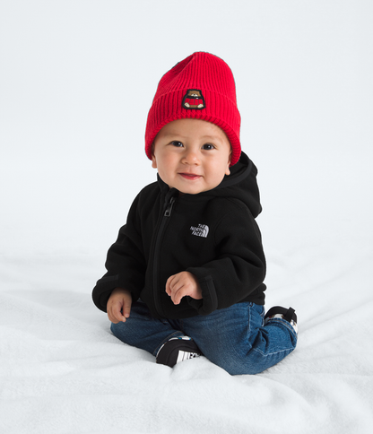 Baby wearing a red beanie and black hoodie on a white background