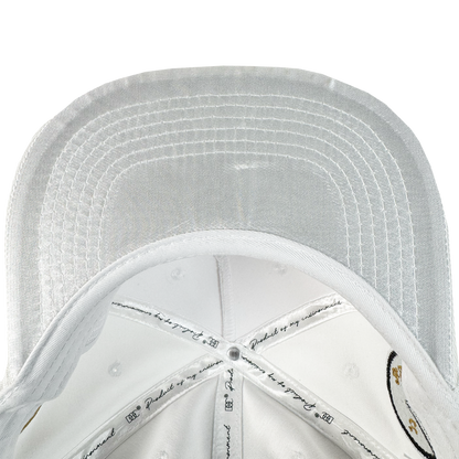 A close-up of the underside of the white Bay Area 5 Panel by DOC from Oaklandish, featuring detailed stitching on the brim and panels, printed text, illustrations, and ventilation holes throughout.