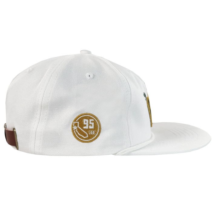 The Bay Area 5 Panel By DOC by Oaklandish is a white, unstructured 5-panel strap back hat with brown and gold embroidery—circle, arrow, “95,” and “LEG.”—stitched eyelets, and a brown back strap, displayed on a plain white background.