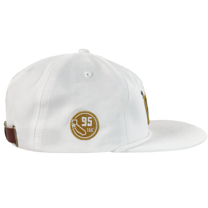 The Bay Area 5 Panel By DOC by Oaklandish is a white, unstructured 5-panel strap back hat with brown and gold embroidery—circle, arrow, “95,” and “LEG.”—stitched eyelets, and a brown back strap, displayed on a plain white background.