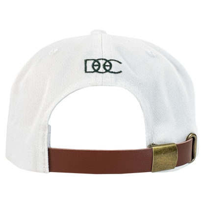 The Bay Area 5 Panel by DOC from Oaklandish features a white strap back, a brown adjustable strap with brass buckle, and green "DCC" embroidery above the opening on the plain white back.