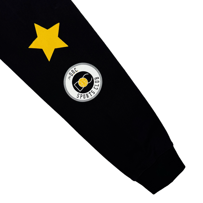 A black sleeve from the Oaklandish Bay Bridge Hoodie By DOC V2, featuring a large yellow star and a round "J02C SPORTS CLUB" patch with shield emblem. Designed for men's fleece hoodies with ribbed sleeve ends on a plain white background.