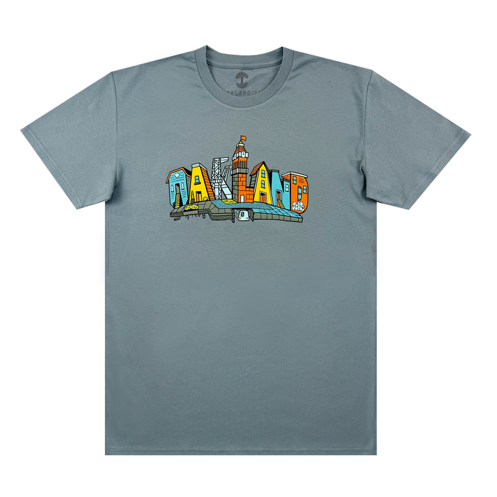 The Oaklandish Blockletters Tee is a gray shirt with a vibrant chest graphic spelling “OAKLAND,” each letter styled as a city landmark, including skyscrapers and the skyline.