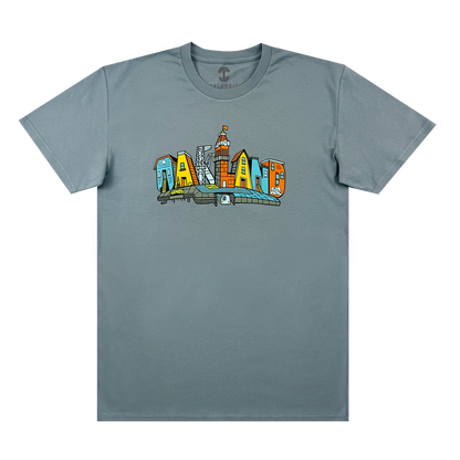 The Oaklandish Blockletters Tee is a gray shirt with a vibrant chest graphic spelling “OAKLAND,” each letter styled as a city landmark, including skyscrapers and the skyline.