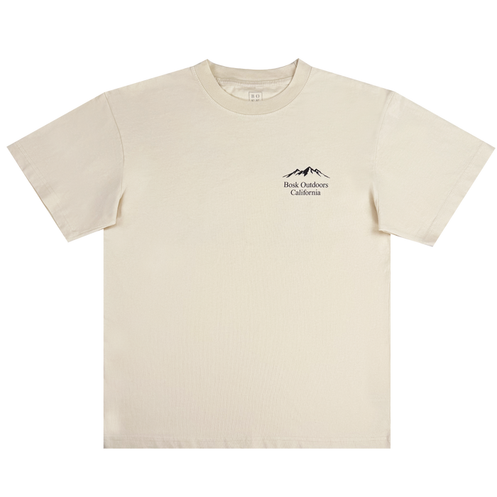 The Bosk Outdoors Tee by Other is a men’s short-sleeved, off-white heavyweight cotton T-shirt featuring a small black line art of mountains above the words “Back Outdoors California” on the upper left chest. The shirt is shown laid flat on a white background.