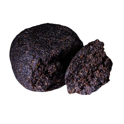 Close-up front view of a dark, crumbly ball and a halved piece of Bubble Yum Hash showing its granular, glistening texture.
