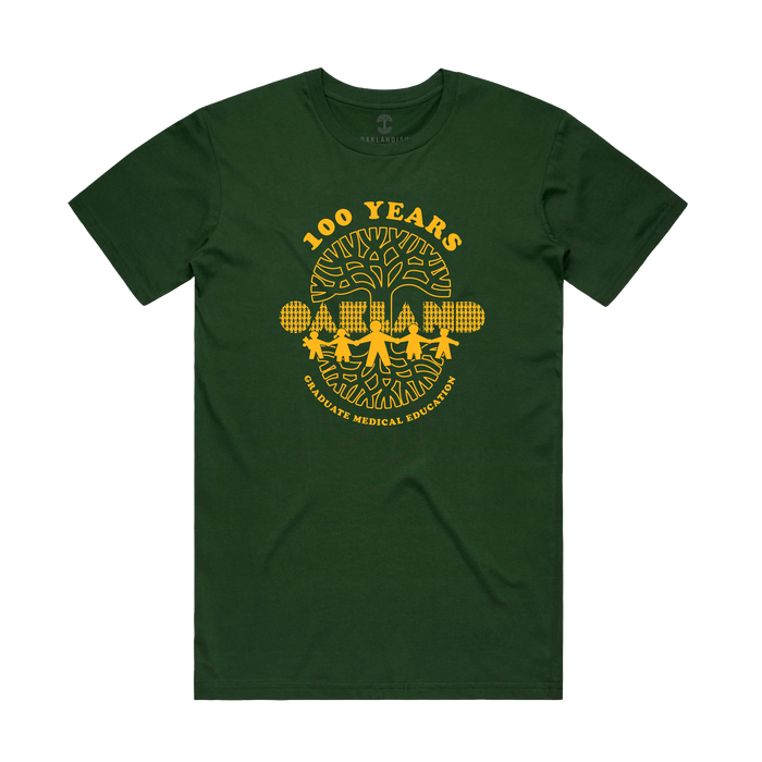Introducing the Oaklandish Century of Caring Tee: a dark green shirt featuring a bold yellow print that reads "100 YEARS GRADUATE MEDICAL EDUCATION" above trees and a city skyline, with "OAKLAND" prominently displayed in block letters in front of the trees. This special edition tee celebrates UCSF Benioff Children’s Hospital Oakland’s century-long commitment to Graduate Medical Education.