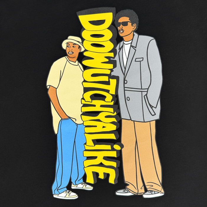 Two illustrated men stand confidently on a black background beside bold yellow text that reads “DOOWUTCHYALIKE.” One sports a yellow shirt, white hat, blue pants, and sneakers; the other wears sunglasses, a gray suit jacket, and tan pants. This Doowutchyalike Tee by Other pays homage to 90s hip hop style—perfect for fans of Oaklandish clothing or Digital Underground.