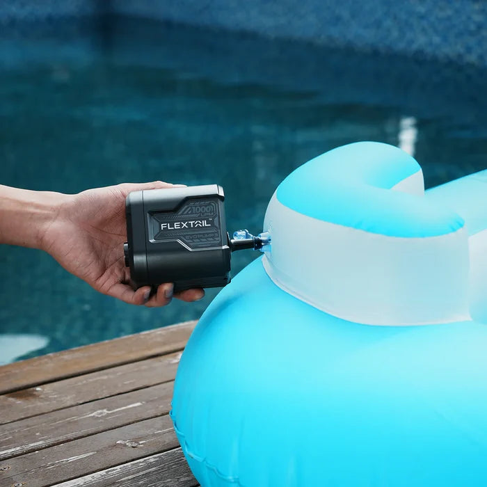Hand holding a device labeled 'FlexTail' attached to a blue inflatable object by a pool.