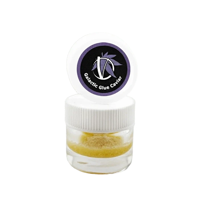 Centered front view of a small clear jar with white lid and purple logo reading Galactic Glue Caviar, showing a golden granular concentrate inside.