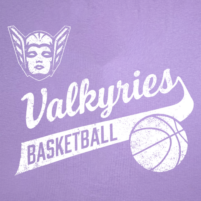 A distressed white graphic featuring a winged, helmeted face, the script word “Valkyries,” “BASKETBALL” in bold block letters on a banner, and a basketball illustration on the right side stands out against a purple background. Printed on GSV’s 100% cotton classic fit GSV Vintage Tee, this design captures the spirit of the Golden State Valkyries.