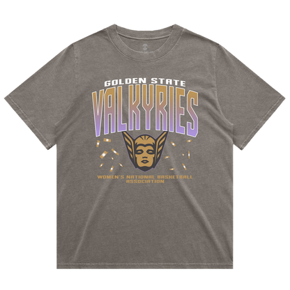 The GSV Women’s First Flight Tee by GSV features an oversized fit in gray, showcasing “Golden State Valkyries” in bold white and purple lettering, a striking gold valkyrie face with wings, and “Women’s National Basketball Association” in smaller gold text beneath. This heavy-weight tee offers both comfort and style for dedicated Golden State Valkyries fans.