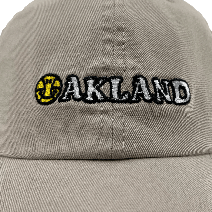 Close-up front view of khaki Oakland Dad Hat, with embroidered wordmark design by Dustin O. Canalin (DOC).