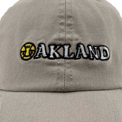 Close-up front view of khaki Oakland Dad Hat, with embroidered wordmark design by Dustin O. Canalin (DOC).