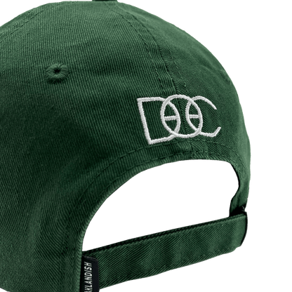 The Happy Oakland Dad Hat by Oaklandish is displayed from the back, showcasing a green corduroy fabric with an adjustable strap and a silver buckle. The back is embroidered with the letters "DCC" in white, featuring a basketball design integrated into the middle "C," reflecting Bay Area culture.