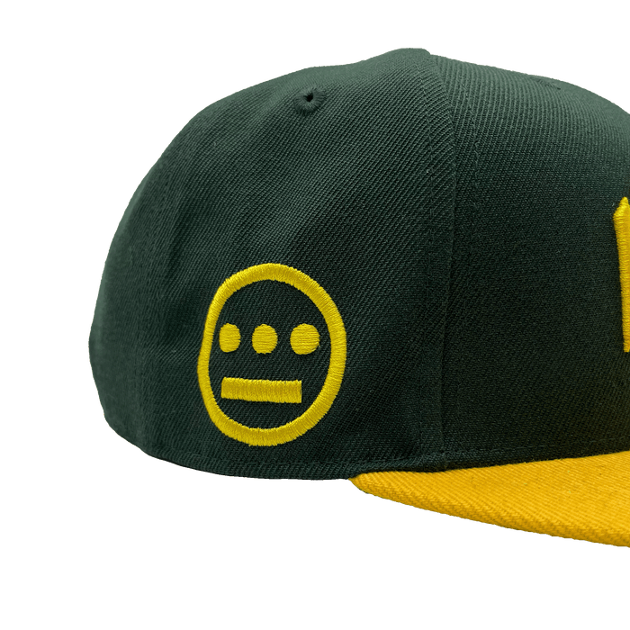 Side view of HIERO logo on the side of a green snapback cap with yellow flat billed visor.