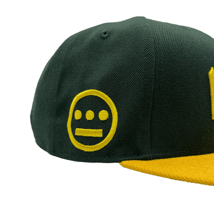 Side view of HIERO logo on the side of a green snapback cap with yellow flat billed visor.