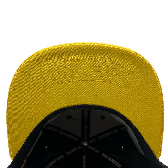 Underside view of flat yellow bill  with OAKLANDISH wordmark taping inside.