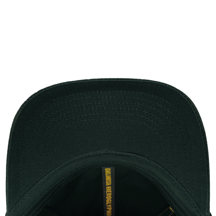 Top view of the Hieroglyphics Hiero Logo Dad Hat shows the inside brim with a darker green shade and visible stitching. Inside, an adjustable strap enhances comfort, while a yellow strip features partially visible black text "QUANSIS NEGROPYHIC," resembling modern hieroglyphics.