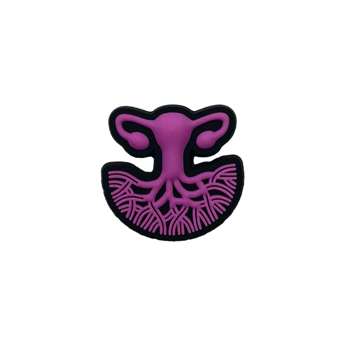 A stylized illustration of the female reproductive system in purple, featuring the uterus, fallopian tubes, and ovaries. The lower section showcases branching blood vessels, while the entire image is outlined in black against a transparent background. This design symbolizes women's healthcare and is presented on the Isha Shoe Charm by Oaklandish.