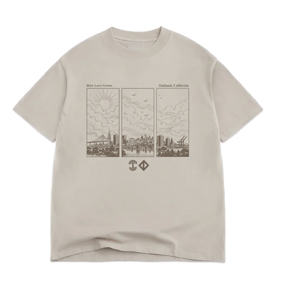 Beige 100% cotton Jwalt X Tidal Tee by Oaklandish in a classic fit, featuring a brown triptych line drawing of Oakland, California’s skyline with clouds, sun, birds, and cranes. The text above reads “How Love Grows” and “Oakland, California,” with two small geometric icons below the illustration.