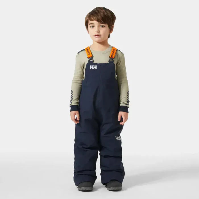 Child wearing navy Helly Hansen bib overalls on a white background