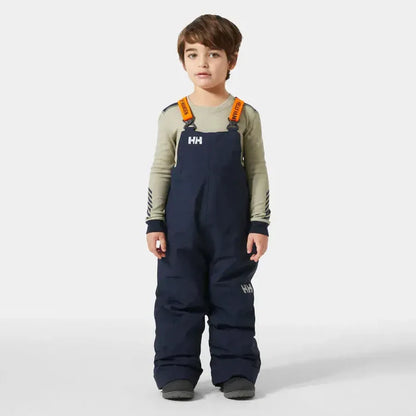 Child wearing navy Helly Hansen bib overalls on a white background