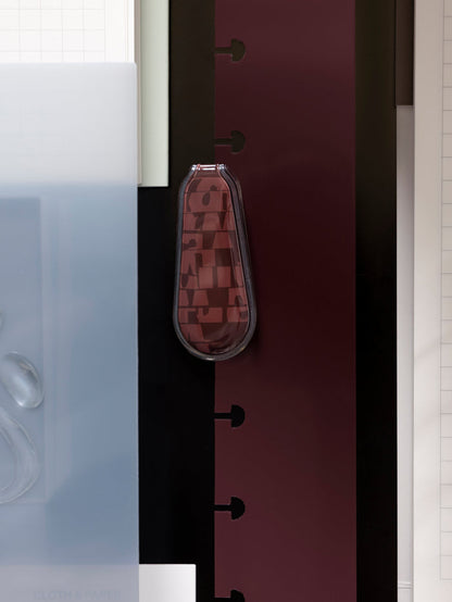 One red, patterned magnetic bookmark shown laying flat on top of various other products.
