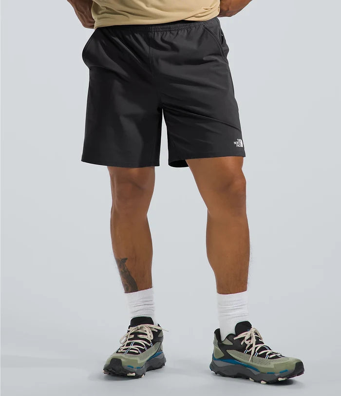 Person wearing black shorts with a brand logo on a light gray background