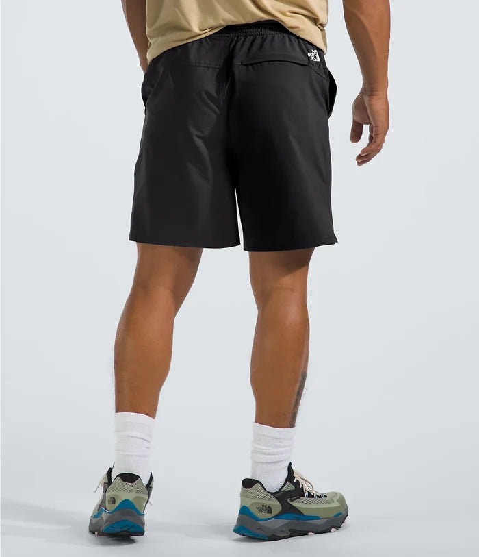 Person wearing black shorts with a brand logo on a light gray background