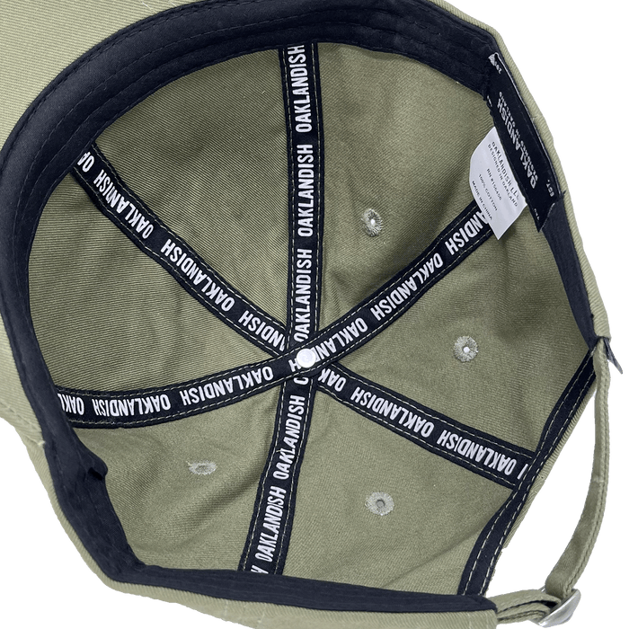 Inside crown view of the black striping inside an army green dad cap with a white Oaklandish wordmark on repeat.