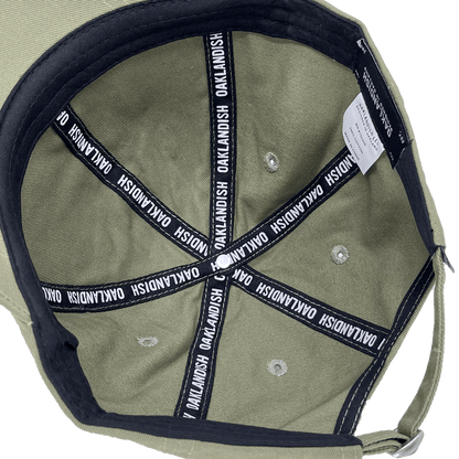 Inside crown view of the black striping inside an army green dad cap with a white Oaklandish wordmark on repeat.