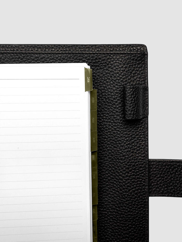 Top right corner close-up of olive green monthly divider in A5 6-Ring Punch planner showing tab label detail