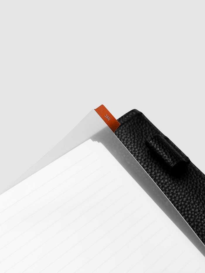 Close-up of deep orange monthly divider lifted from A5 6-Ring Punch planner showing colored background and clear knockout month text