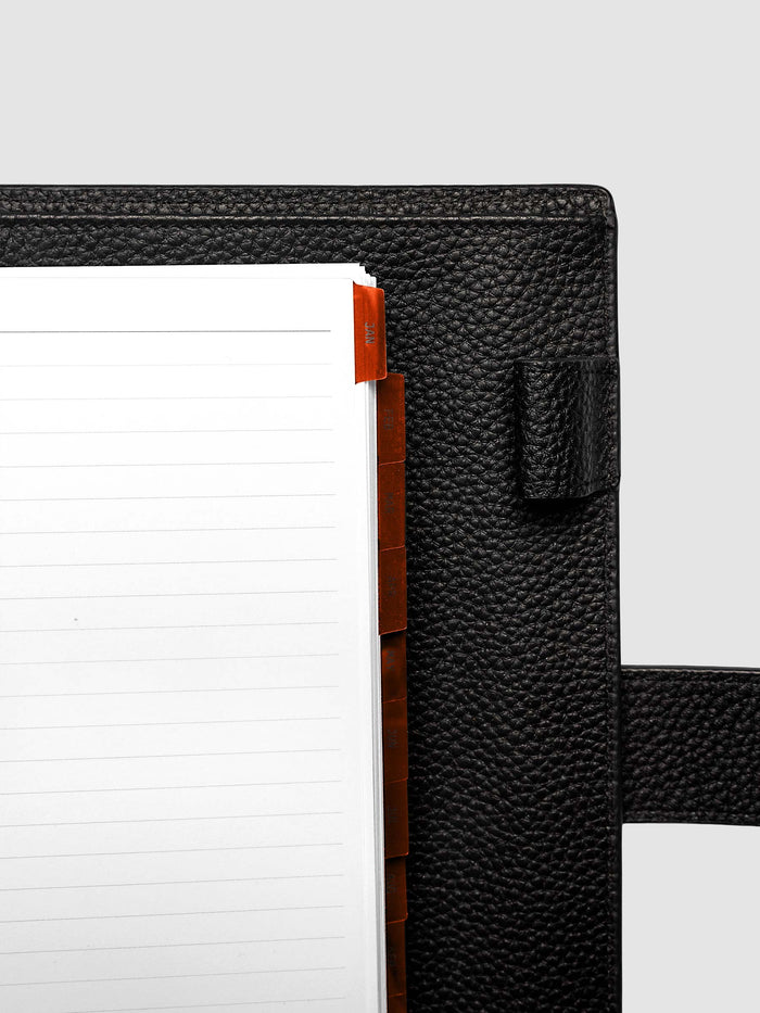 Top right corner close-up of deep orange monthly divider in A5 6-Ring Punch planner showing tab label detail