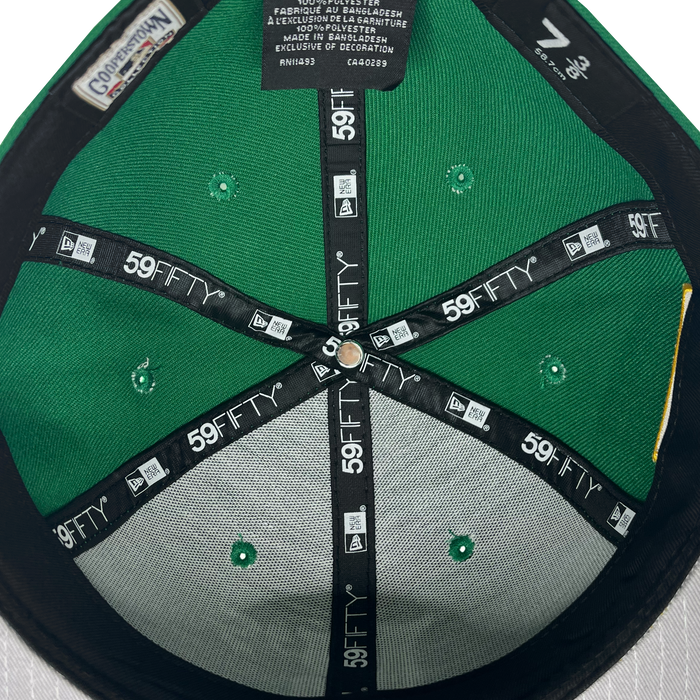 The image shows the inside of a New Era Oakland Ballers 59Fifty Cap, likely worn by an Oakland Ballers fan. The interior includes black lining adorned with repeated white "59FIFTY" text and logos. Visible tags provide details on size, manufacturing, and materials in English, Spanish, and French. The cap is size 7 3/8.