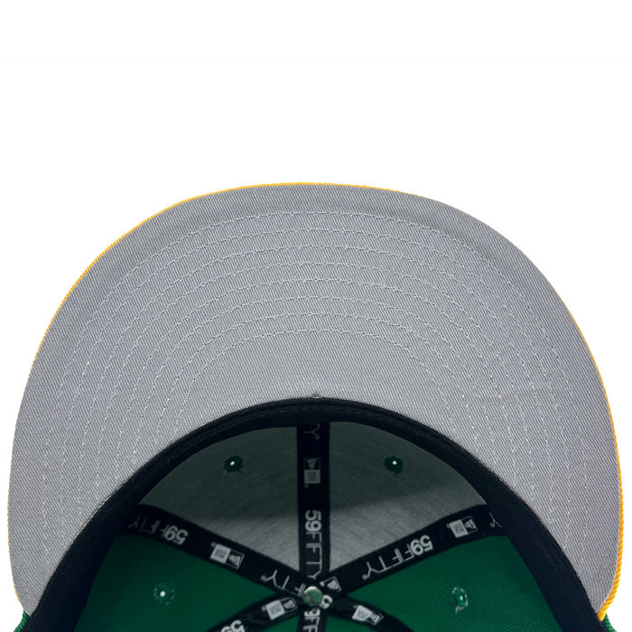A close-up view of the underside of a New Era Oakland Ballers 59Fifty Cap's brim from their Pioneer League days. The brim is gray with visible stitching and a yellow edge. The interior showcases green fabric and black bands labeled "39THIRTY." Rivets on the green fabric are also evident, against a white background.