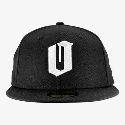 A black New Era Official 59FIFTY Fitted Cap by Other showcases a prominent, stylized white “U” embroidered on the front panel. The cap includes a round button at the crown and features the iconic 59FIFTY sticker on its flat brim. Set against a plain white background, the image highlights the cap’s unique design and detailing.