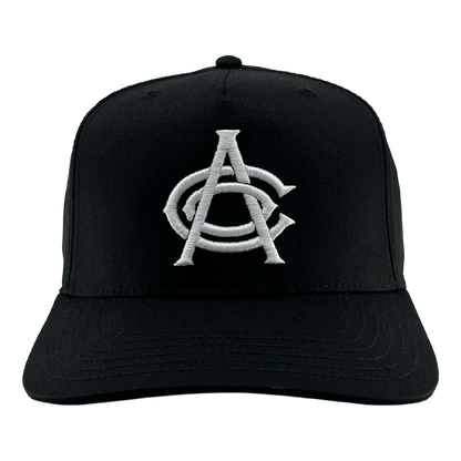 Introducing the OAC Logo 5 Panel by OAC—a black snapback cap featuring a white embroidered logo of interlocking “A” and “C” letters in a bold, stylized font, representing the Oakland Athletic Club. This cap is designed with a curved brim and visible stitching on both the bill and crown, showcased against a plain white background.