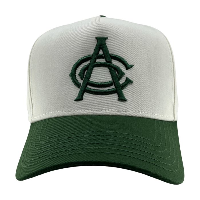 The OAC Logo 5 Panel by OAC is a baseball snapback cap featuring a white front panel and a green bill. The cap displays an embroidered green Oakland Athletic Club logo with two overlapping letters, “A” and “C,” on the front. The background is plain white.