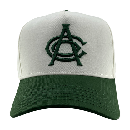 The OAC Logo 5 Panel by OAC is a baseball snapback cap featuring a white front panel and a green bill. The cap displays an embroidered green Oakland Athletic Club logo with two overlapping letters, “A” and “C,” on the front. The background is plain white.