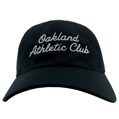 A front view of the OAC Script Dad Hat by OAC, in black, featuring “Oakland Athletic Club” embroidered in white cursive on the front and an adjustable back strap, set against a plain white background.